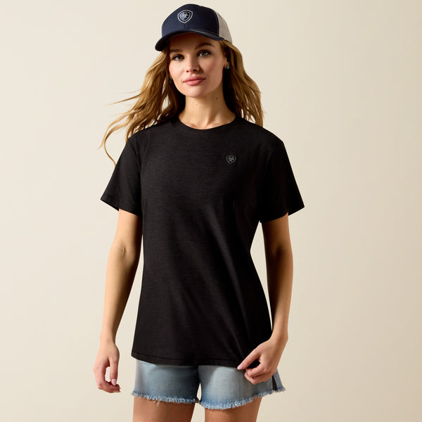 Woman wearing a black t-shirt and denim shorts with a beige background
