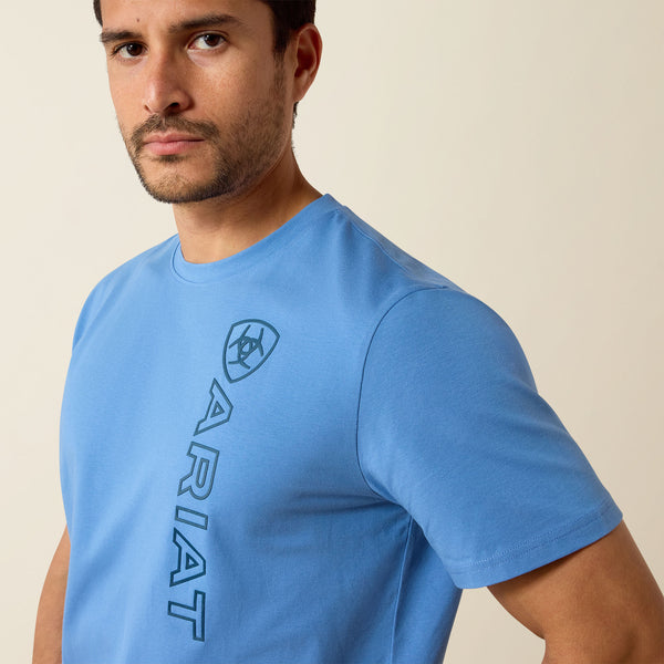 Man wearing a blue Ariat t-shirt against a beige background