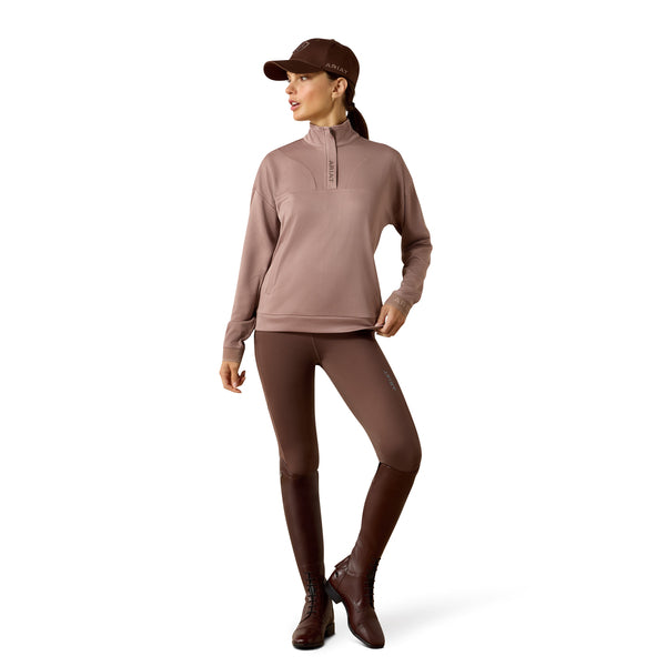 Woman wearing a brown equestrian outfit with a hat on a white background