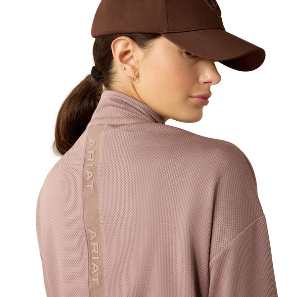 Person wearing a brown Ariat cap and pink jacket on a white background