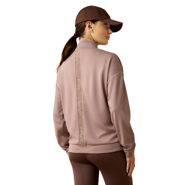 Woman wearing a pink jacket with brand logo on the back against a white background