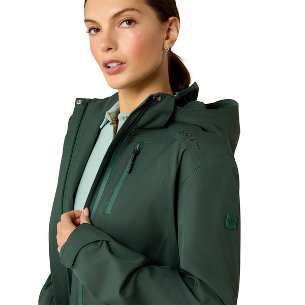 Woman wearing a green jacket with ariat brand logo on a white background