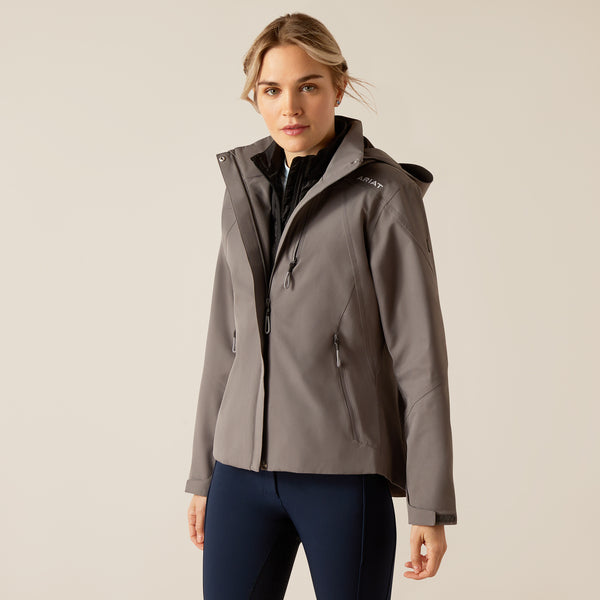 Woman wearing a gray jacket with a hood on a beige background