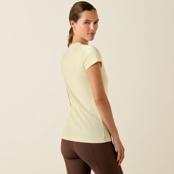 Woman wearing a light yellow t-shirt and brown pants on a beige background