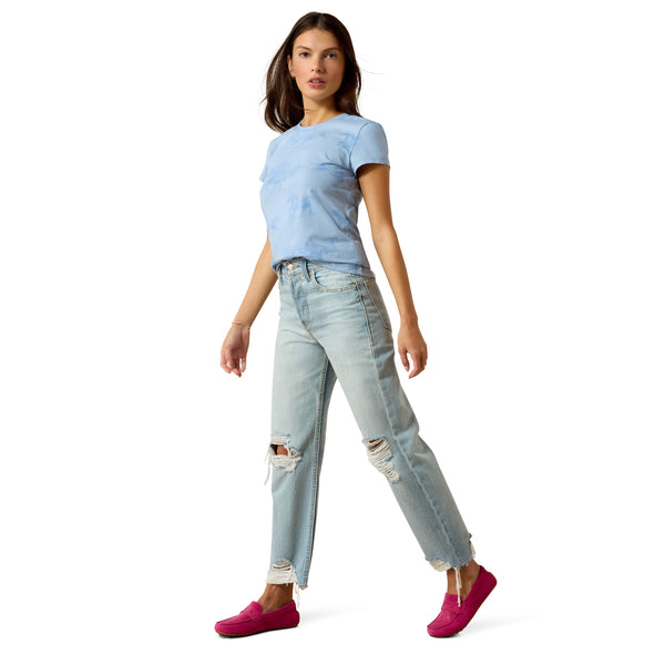 Woman wearing a light blue t-shirt and ripped jeans on a white background