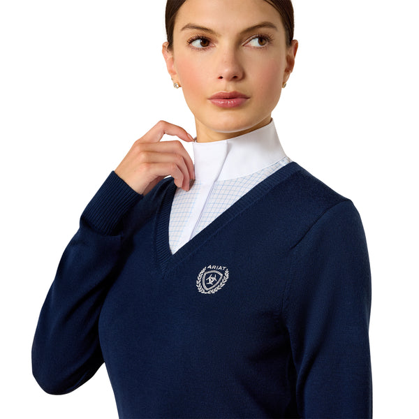 Woman wearing a navy blue sweater with a logo, white shirt underneath on a white background