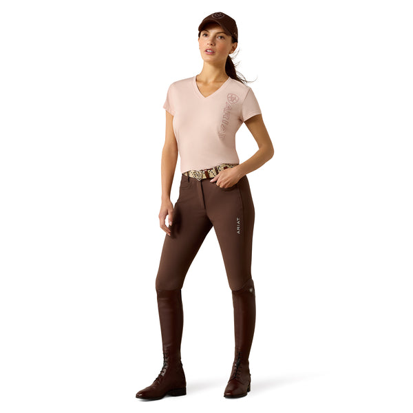 Woman wearing a beige top and brown riding pants on a white background