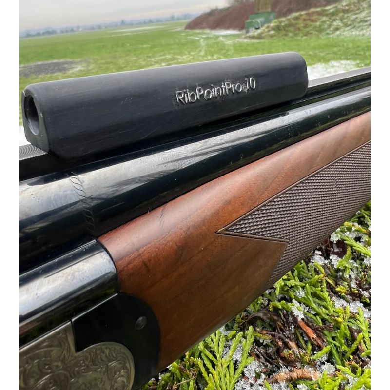 Close-up of a rifle with a ribbed point pad on a grassy background